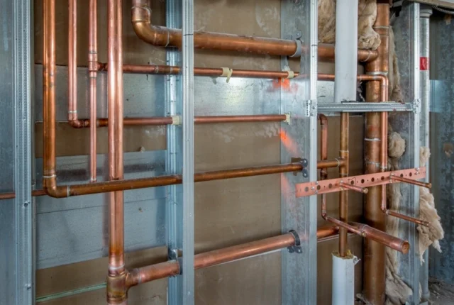 Neatly installed copper water supply lines and shut-off valves inside an open wall